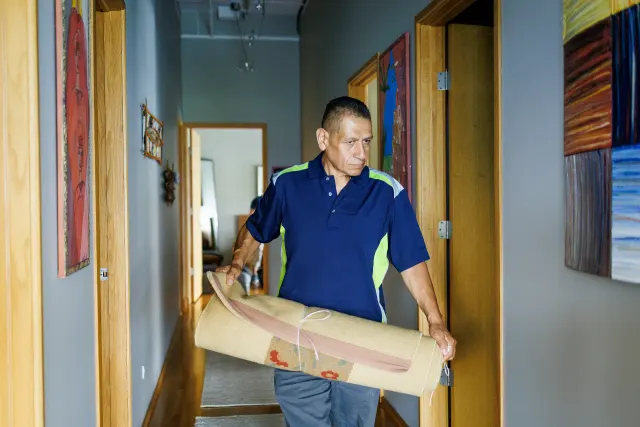 Premier crew member carrying a rolled rug through a doorway