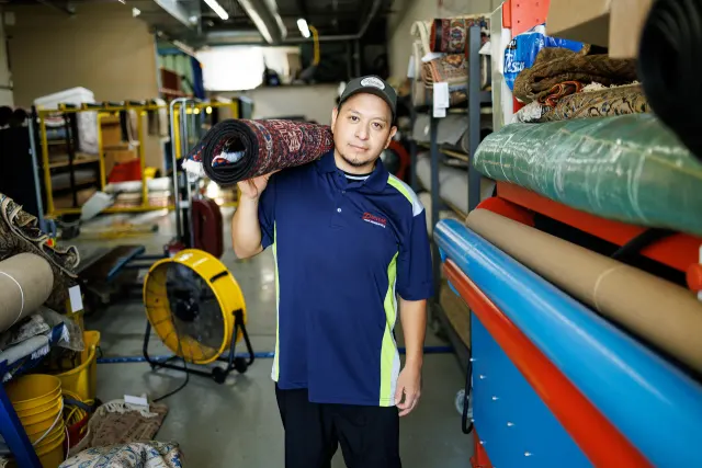 Technician carrying a rug into the Premier cleaning plant