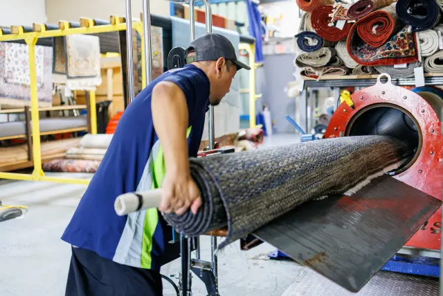 Technician feeding a rolled rug into the centrifuge