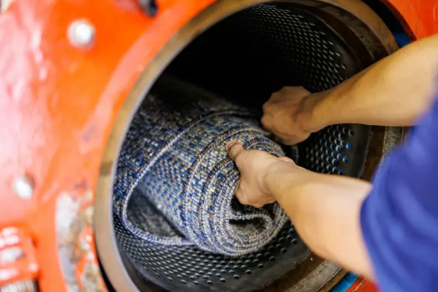 Crew member loading a rolled rug into the centrifuge after washing