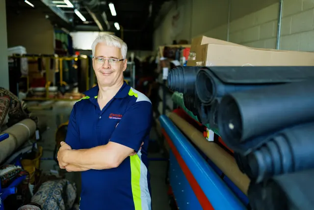 Premier team member beside rolls of rug pad material