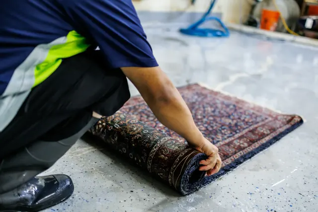 Crew member rolling a clean Oriental rug for the trip back