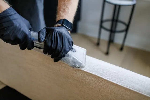 Close-up of an upholstery tool cleaning a sofa arm