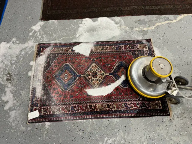Small tribal rug being scrubbed with a rotary machine